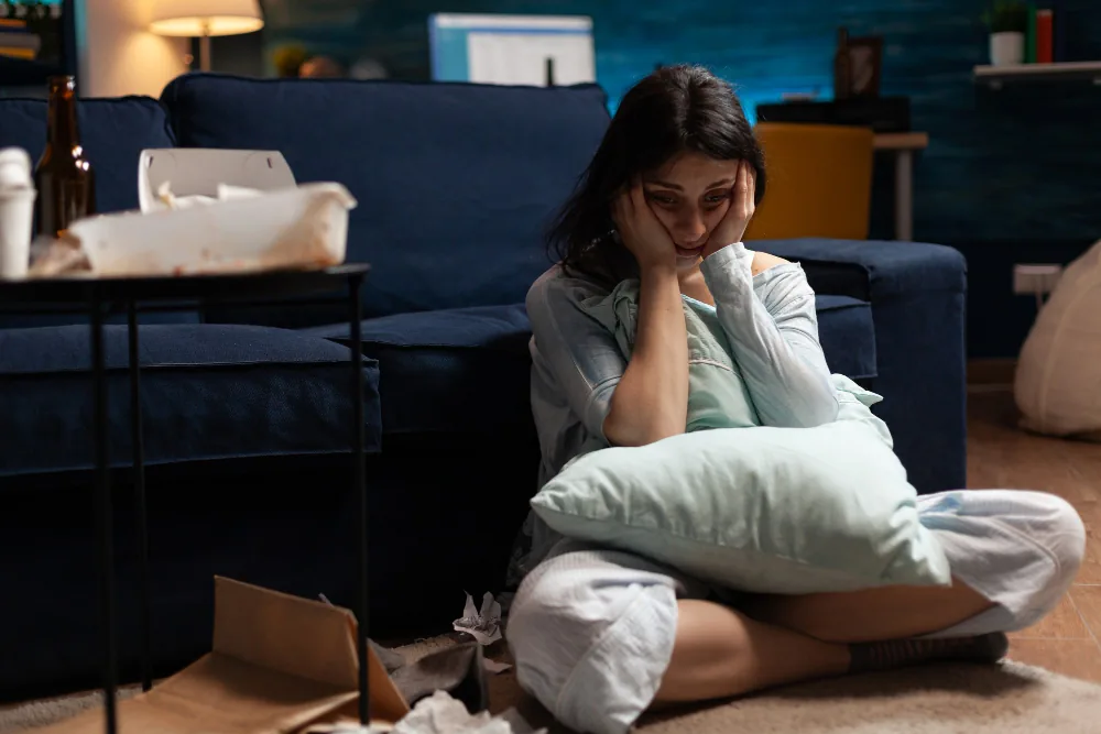 Woman sitting alone at home while reflecting on persistent low mood and social withdrawal